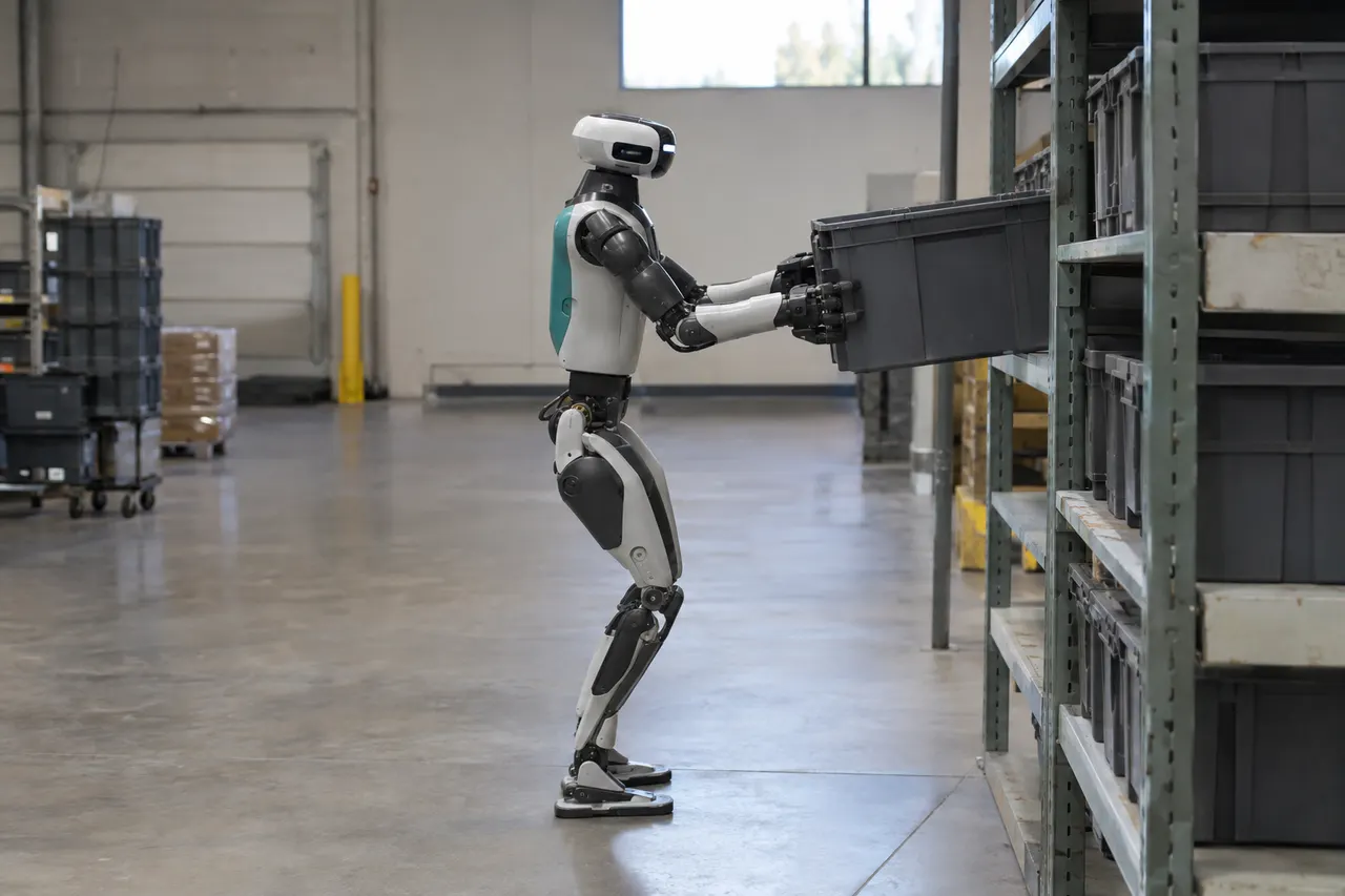 Humanoid robot lifts a plastic bin onto a warehouse shelf, surrounded by storage racks and industrial shelving.