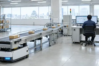 Worker monitors conveyor belts and package movement on computer screens in a modern, automated warehouse facility.